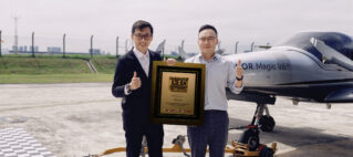 Two men in suits pose with an ASEAN Records plaque beside a small aircraft on a runway, thumbs up.
