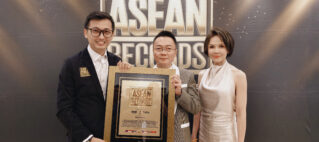 Three people pose with a framed ASEAN Records award in front of a dark backdrop with a large ASEAN logo.