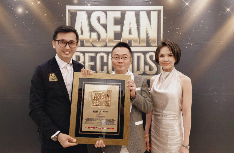 Three people pose with a framed ASEAN Records award in front of a dark backdrop with a large ASEAN logo.