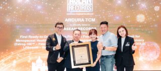 Five professionals pose on a stage, holding a framed trophy at an ASEAN Records award ceremony.