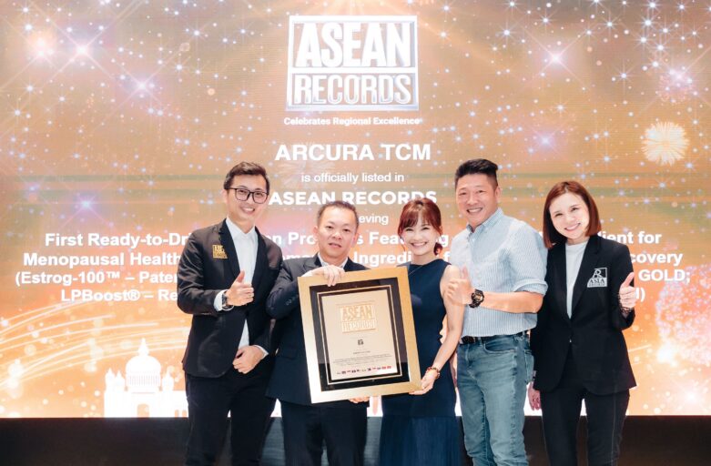 Five professionals pose on a stage, holding a framed trophy at an ASEAN Records award ceremony.