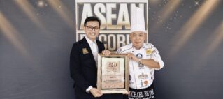 Two men pose with a framed ASEAN Records certificate at an awards event, one in a suit, the other in a chef's uniform and hat.