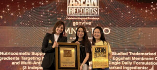 Three women stand on a stage holding ASEAN Records plaques, smiling at the camera with a branded backdrop behind them.