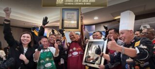 Celebration scene with chefs and staff holding a framed ASEAN Records certificate for the 'Longest Line of Laksa Johor' and giving thumbs up.