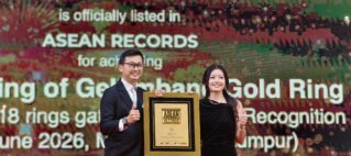 Two presenters pose with a framed ASEAN Records award on stage, smiling at the ceremony with a large, text-filled screen behind them.