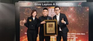 Three people in black attire posing with a framed award on a lit stage backdrop that reads 'Give Laptop A Second Life.'
