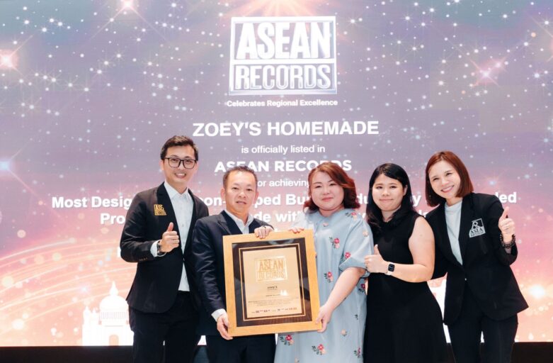 Five professionals pose on a stage holding a framed award in front of a backdrop that reads ASEAN RECORDS and celebrates regional excellence, thumbs up all around