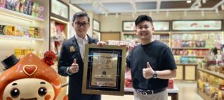 Two men in a store pose with a framed ASEAN Records plaque, giving thumbs up.