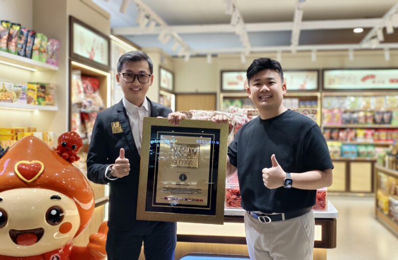 Two men in a store pose with a framed ASEAN Records plaque, giving thumbs up.