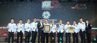 Group of men and women in white uniforms on stage, holding certificates and posing for a photo at an awards event with ASEAN Records backdrop.