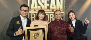 Four people pose on a red carpet backdrop with a large ASEAN RECORDS sign, holding a gold-framed award plaque and giving thumbs up.
