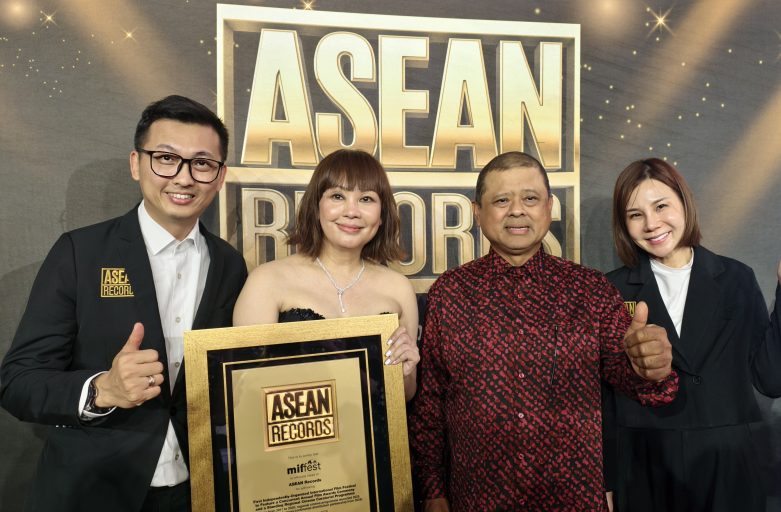 Four people pose on a red carpet backdrop with a large ASEAN RECORDS sign, holding a gold-framed award plaque and giving thumbs up.