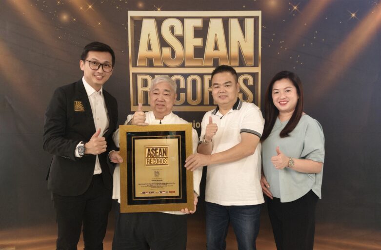 Four people posing with a gold-framed ASEAN Records plaque at an awards event, giving thumbs up.
