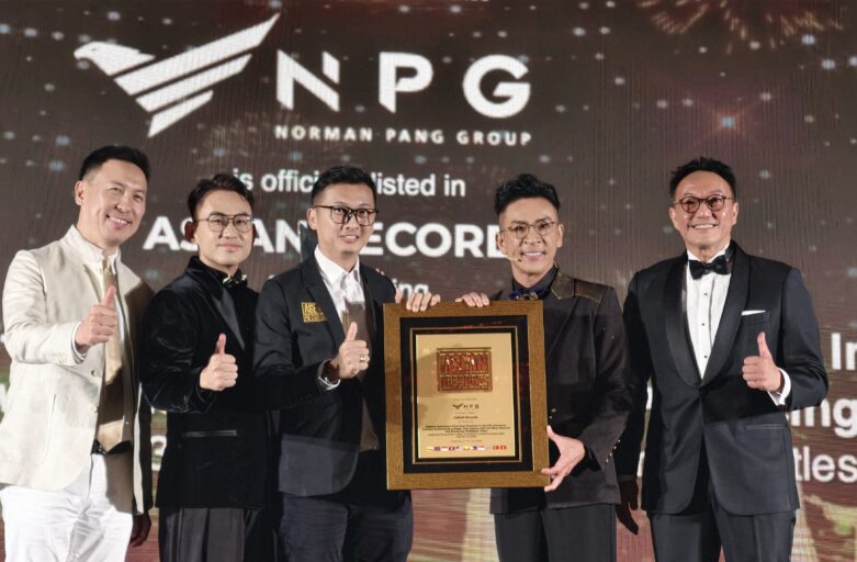 Five men in formal attire pose on stage with a large framed award plaque, giving thumbs up at an award ceremony.