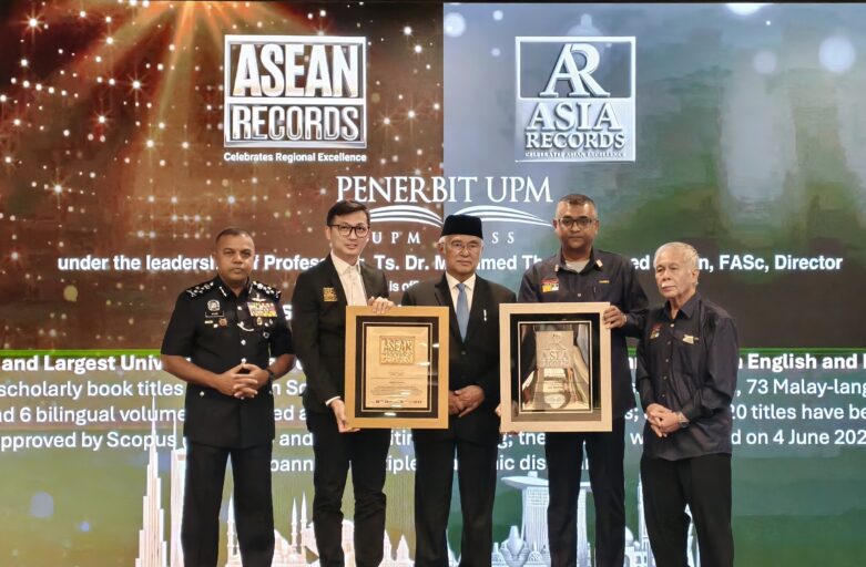 Group of men in formal attire posing with framed awards on a stage at an ASEAN Records event, with glowing backdrop and logos in the background.