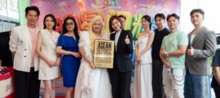 Group of nine people posing on a red carpet holding an ASEAN Records plaque at a colorful event backdrop.