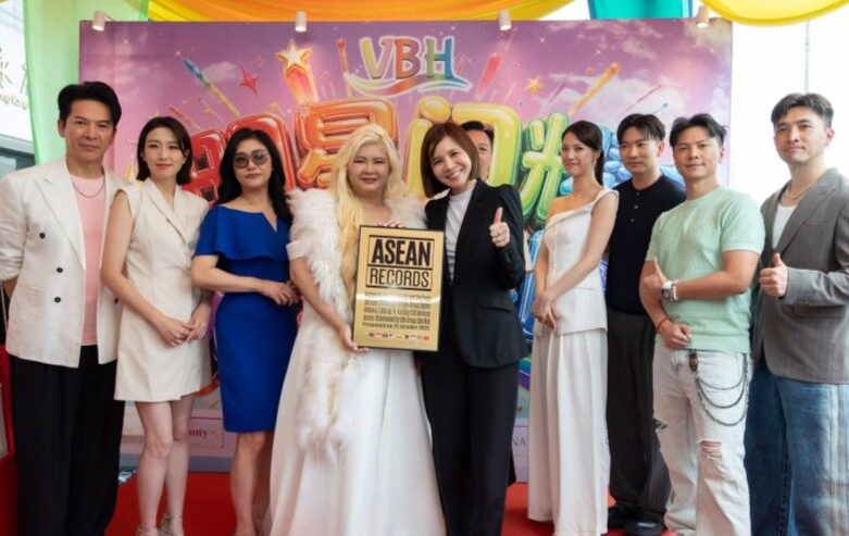 Group of nine people posing on a red carpet holding an ASEAN Records plaque at a colorful event backdrop.