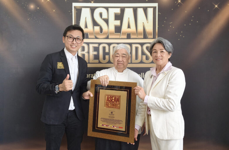 Three people pose with a framed award in front of an ASEAN Records backdrop.