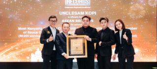 Five professionals in suits on a stage holding a framed award at an ASEAN Records ceremony backdrop.