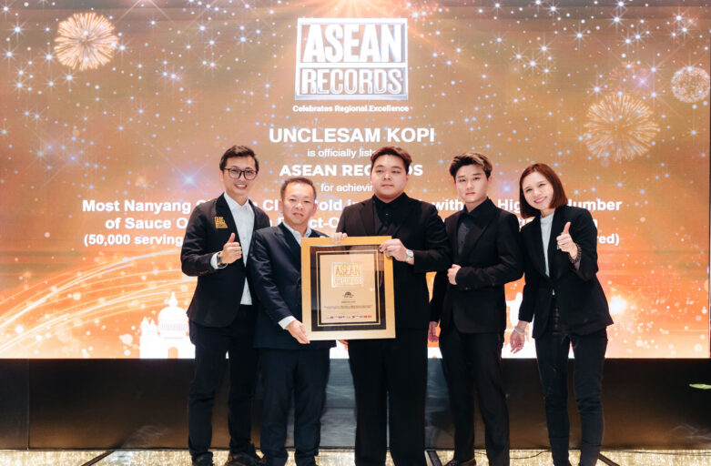 Five professionals in suits on a stage holding a framed award at an ASEAN Records ceremony backdrop.