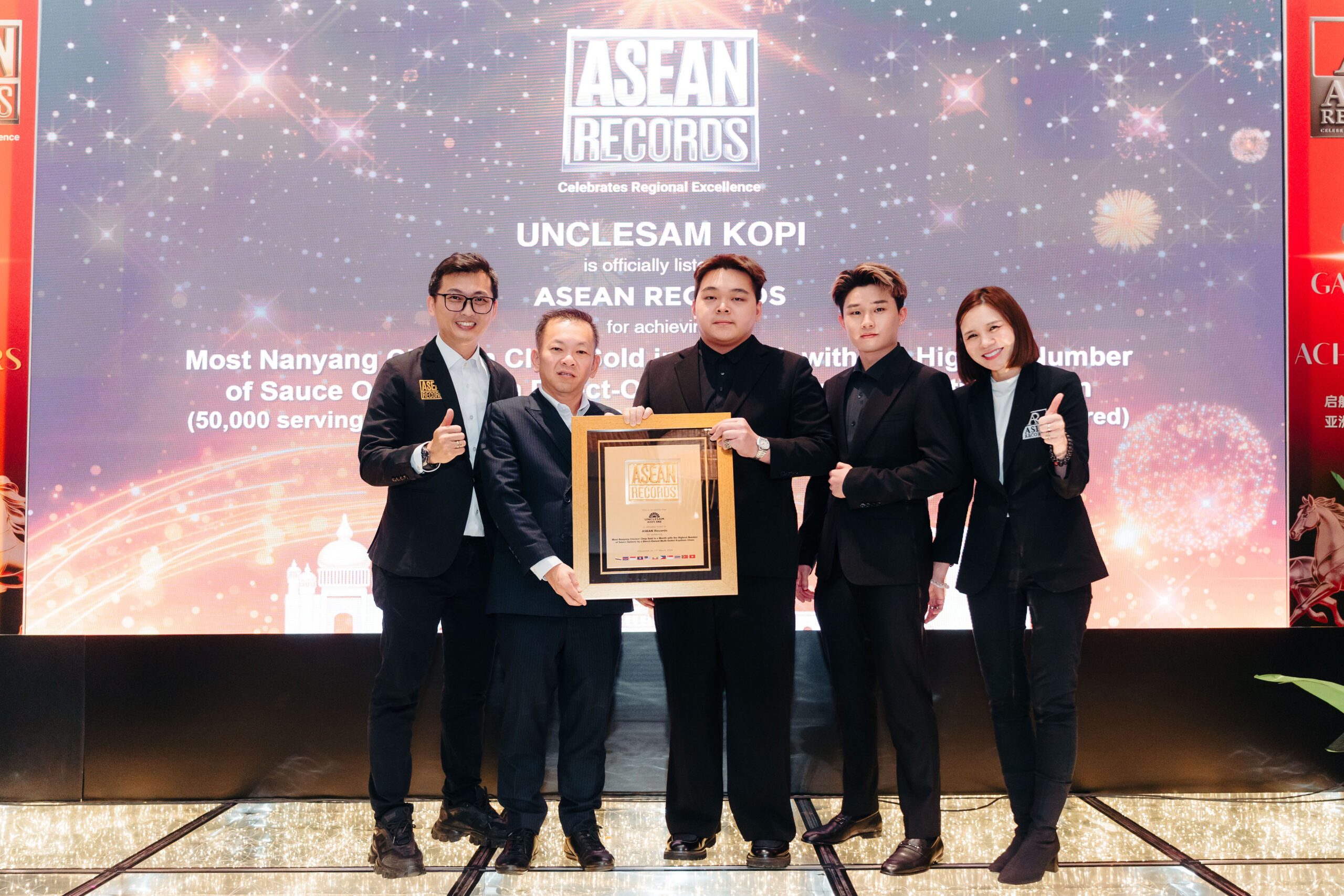 Five people in suits pose on a lit stage holding a framed ASEAN Records award plaque with a starry backdrop.