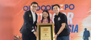 Three people pose with a tall gold-framed award plaque at an ASEAN Records event against an orange backdrop.