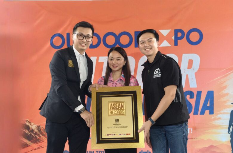 Three people pose with a tall gold-framed award plaque at an ASEAN Records event against an orange backdrop.